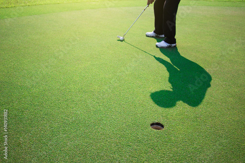 Photography Golfer putting golf ball on the green golf