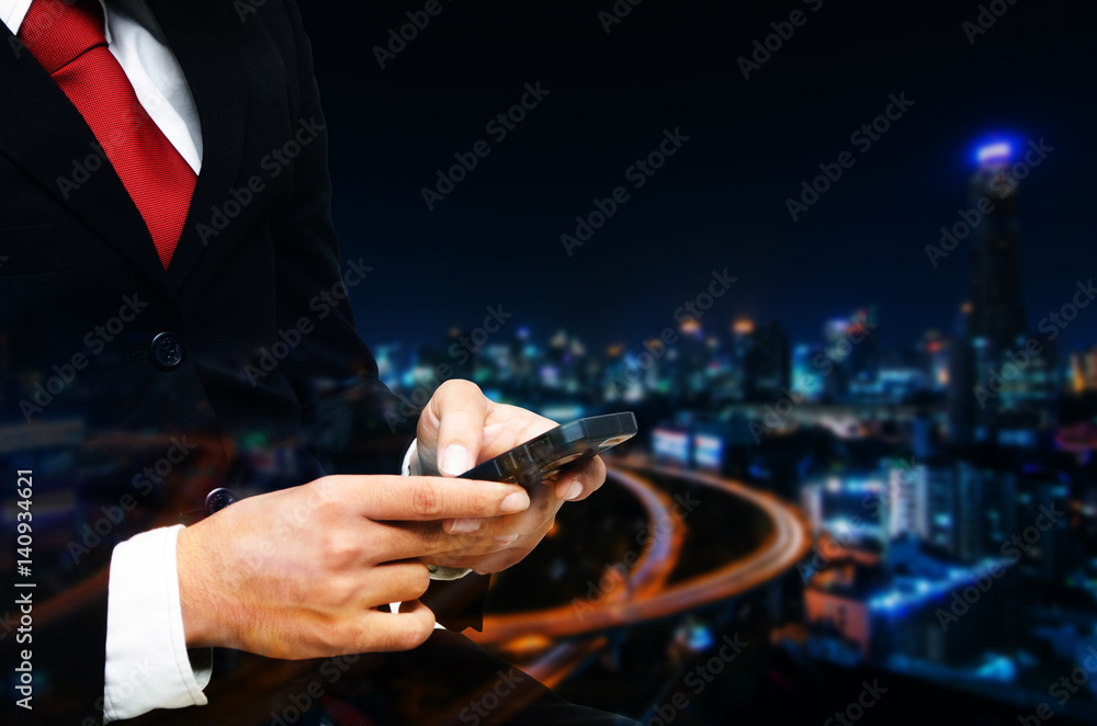 businessman in suit  and red necktie using smart phone on blurred night city background, network connection and technology concept, color tone effect.