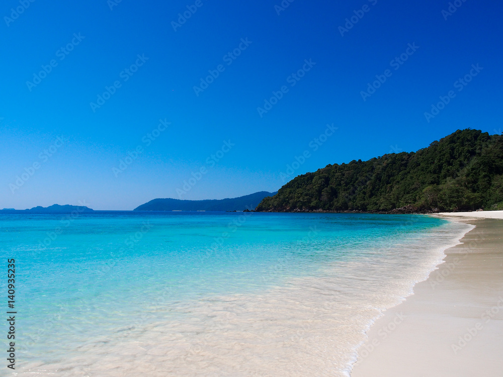 Sea and white sand beach with clear blue sky