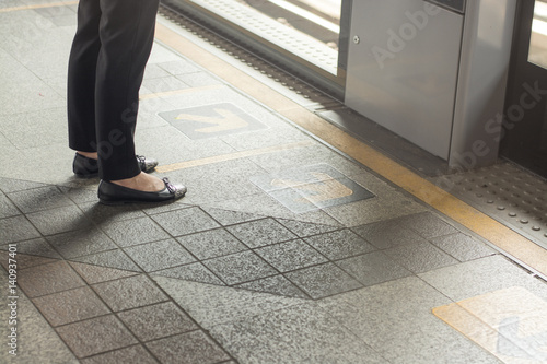 female feet standing on platform waiting train at the station