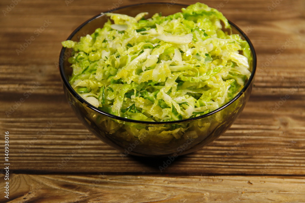 Savoy cabbage salad in glass bowl on wooden table Savoy cabbage salad in glass bowl on wooden table