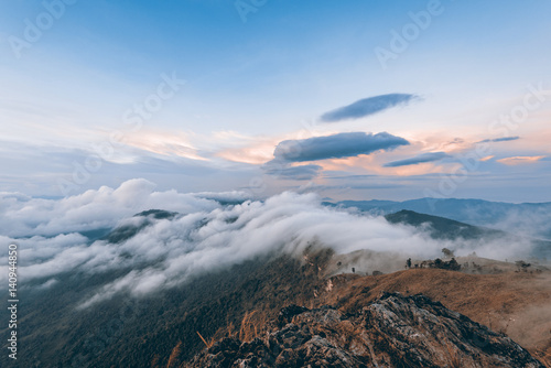 Vintage style beautiful landscape nature of sunrise on peak mountain with cloud fog and sky in winter at Phu Chi Fa Forest Park, Chiang Rai, Thailand, on Sienna-Blue color two tone
