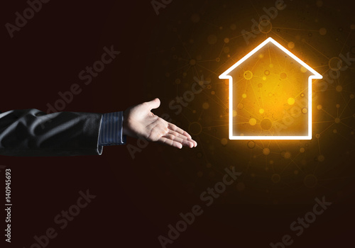 Conceptual image with hand pointing at house or main page icon on dark background