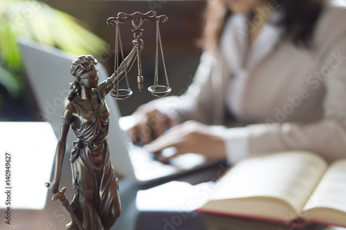Statue of Justice and lawyer working on a laptop