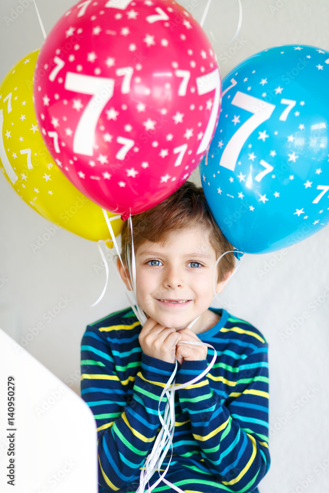 Portrait of happy kid boy with bunch on colorful air balloons on 7 birthday