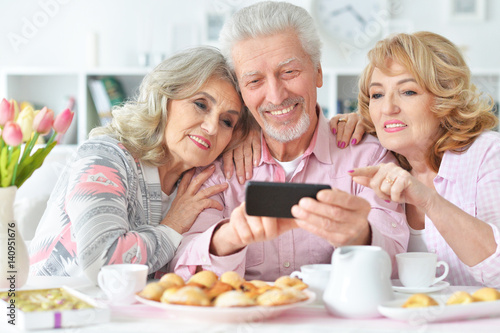 Elderly people having breakfast and using mobile phone