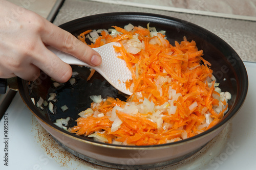onions and carrots in a hot frying pan