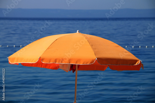 Orange beach umbrella near the Adriatic sea in Brela , Croatia 