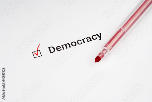 Questionnaire. Red marker and the inscription democracy with check mark on the white paper