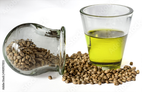 Hemp seeds and hempseed oil in a glass beaker on a white background. Selective focus.
