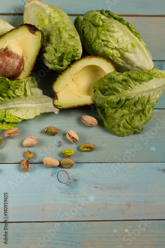 Avocado, romaine lettuce and pistachios. Green. Blue wooden table. 