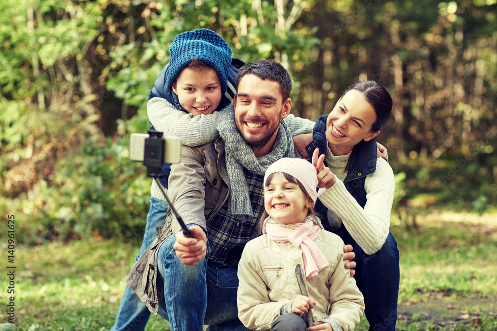 happy family with smartphone selfie stick in woods happy family with smartphone selfie stick in woods