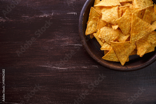 Nachos chips. Delicious salty tortilla snack on rustic plate. On wooden table background.