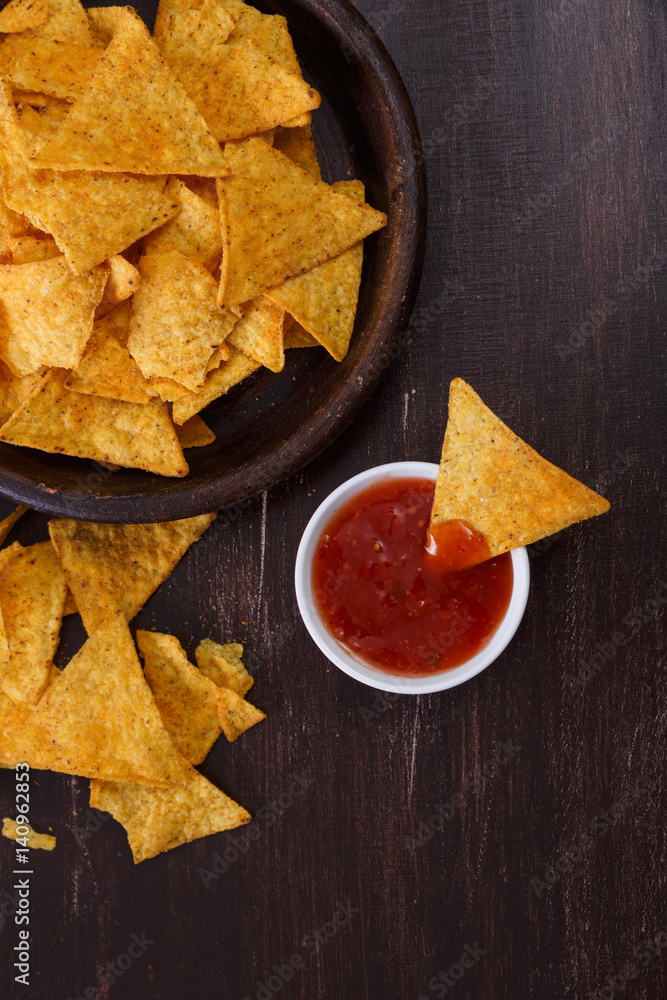 Nachos chips. Delicious salty tortilla with sweet salsa or chilli sauce on wooden background. Snack on rustic plate. Nachos chips. Delicious salty tortilla with sweet salsa or chilli sauce on wooden background. Snack on rustic plate.