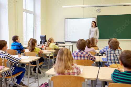 group of school kids with teacher in classroom