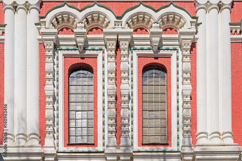 Ornate windows with white frames and red brick wall