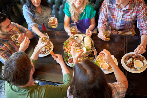 Quadro su tela happy friends eating and drinking at bar or pub