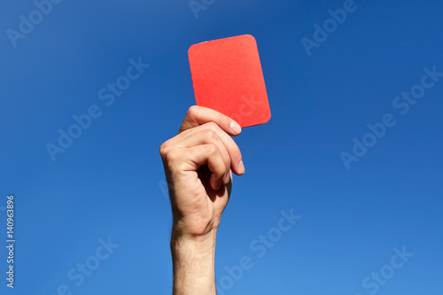 Vászonkép referee hands with red card on football field