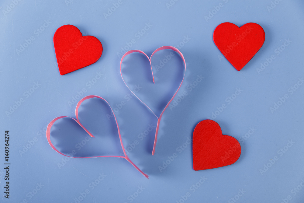 Paper and red wooden hearts on blue background. Concept for romantic love. Valentines day design.