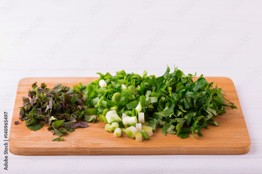 Chopped mint, green onions and parsley in bowl Chopped mint, green onions and parsley in bowl