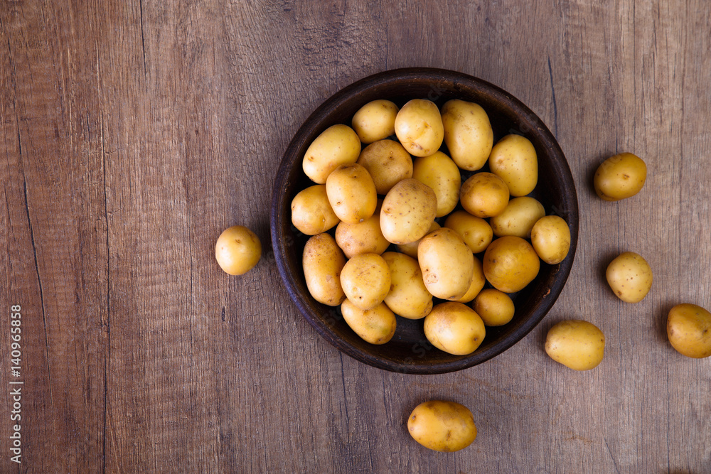 Potatoes in plate. Raw new potato. Fresh natural vegetables. Organic bio food on rustic wooden table. Potatoes in plate. Raw new potato. Fresh natural vegetables. Organic bio food on rustic wooden table.