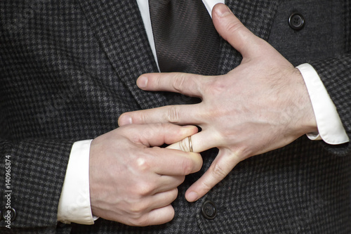 a man in jacket struggling to remove wedding ring from his finger