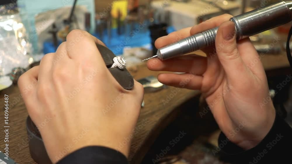 Goldsmith drill a silver ring using a special tool on the table Goldsmith drill a silver ring using a special tool on the table