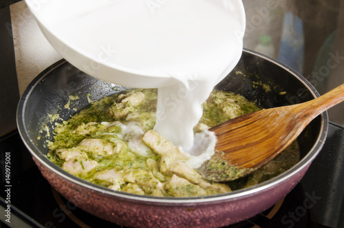 Thai food cooking, Pouring coconut milk into a pan to making green curry photo