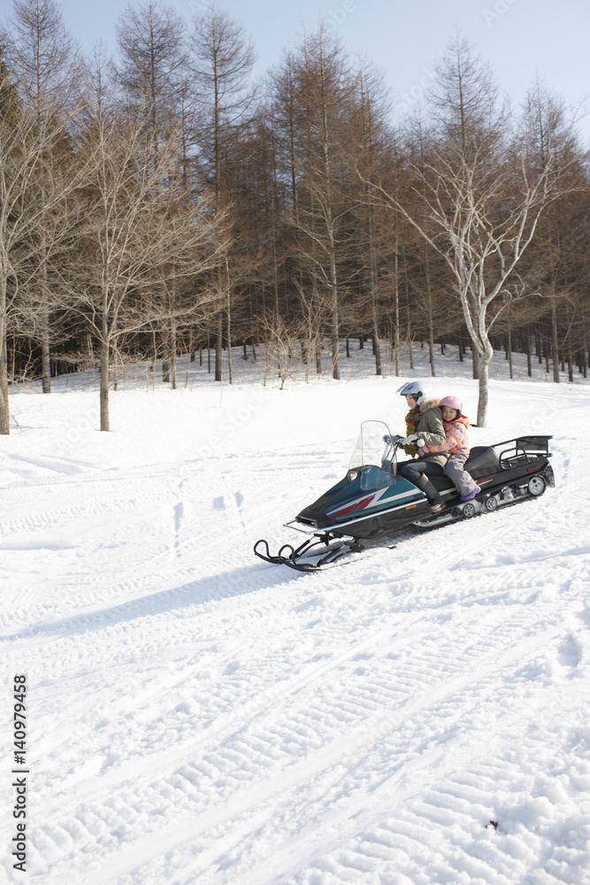 Mother and child riding on snowmobile 