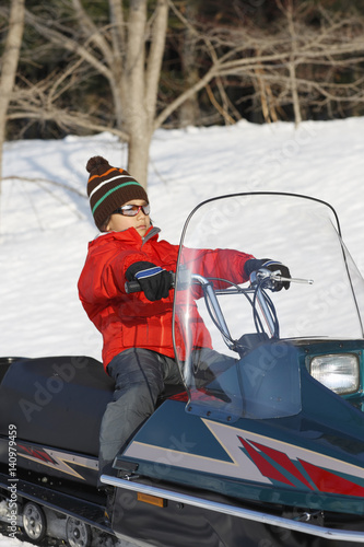 A boy riding on snowmobile 