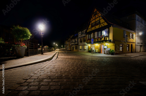 Evening view of old houses in the town of Colmar. Alsace. France.  Street lights are burning. © Анатолий Еремин