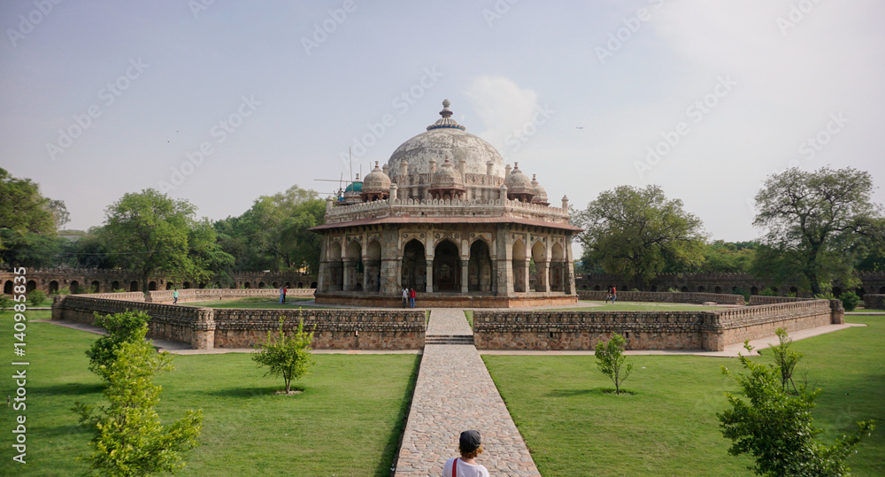 Young woman walking on path towards ancient Indian landmark with dome