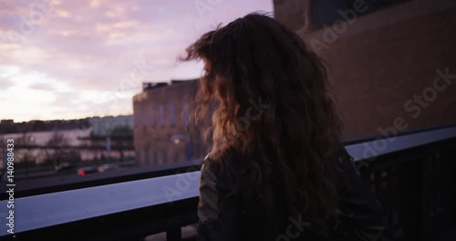 Young woman walks up to balcony, sunset