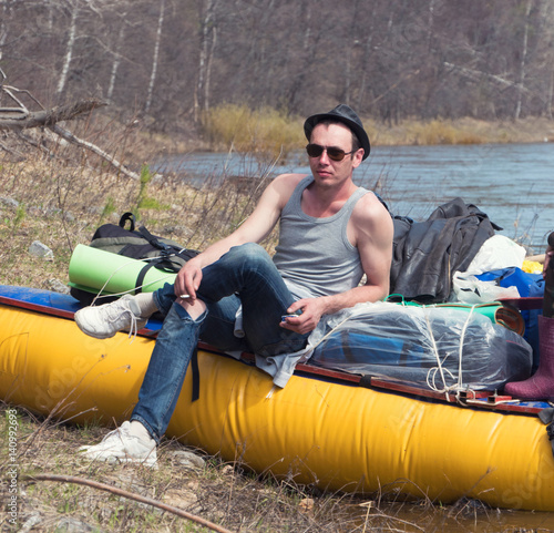 Water traveling - young Man in hat and sunglasses on tourist catamaran at forest river photo