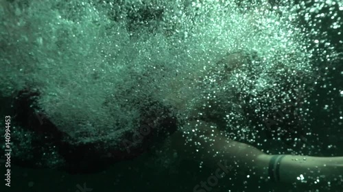 Woman jumps underwater at night, slow motion