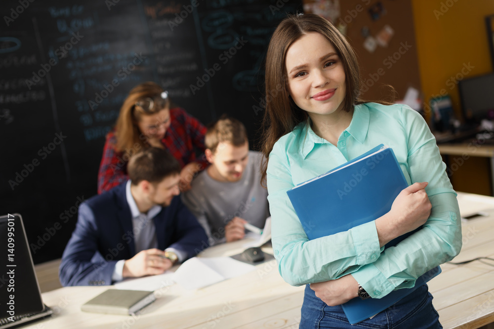 Businesswoman posing while others business people talking in background Businesswoman posing while others business people talking in background