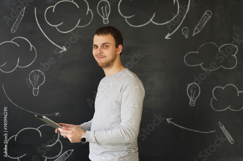 Young man with tablet by the wall photo