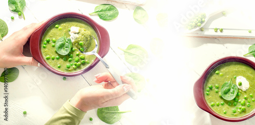 Woman hands with Bowl of healthy green pea soup.