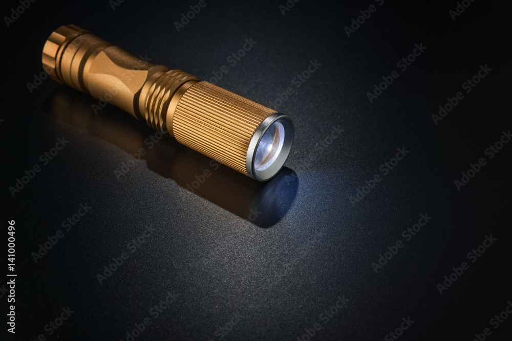 Golden flashlight on dark surface. Golden flashlight on dark surface.