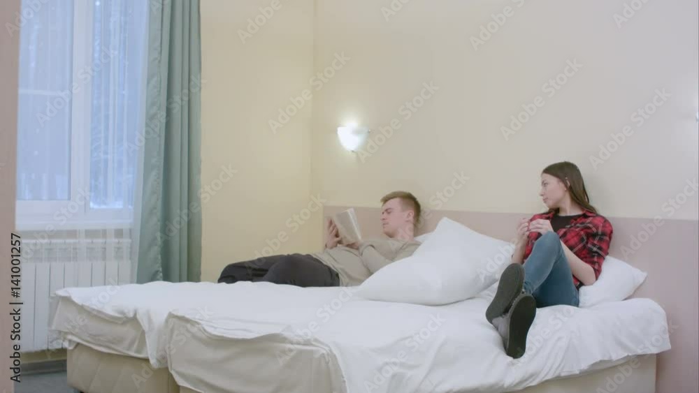 Pretty girl disturbs her boyfriend, while he was reading and the couple start to fight with pillows Pretty girl disturbs her boyfriend, while he was reading and the couple start to fight with pillows