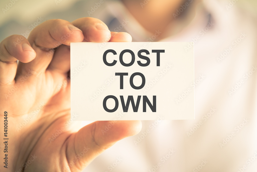 Businessman holding COST TO OWN message card Businessman holding COST TO OWN message card