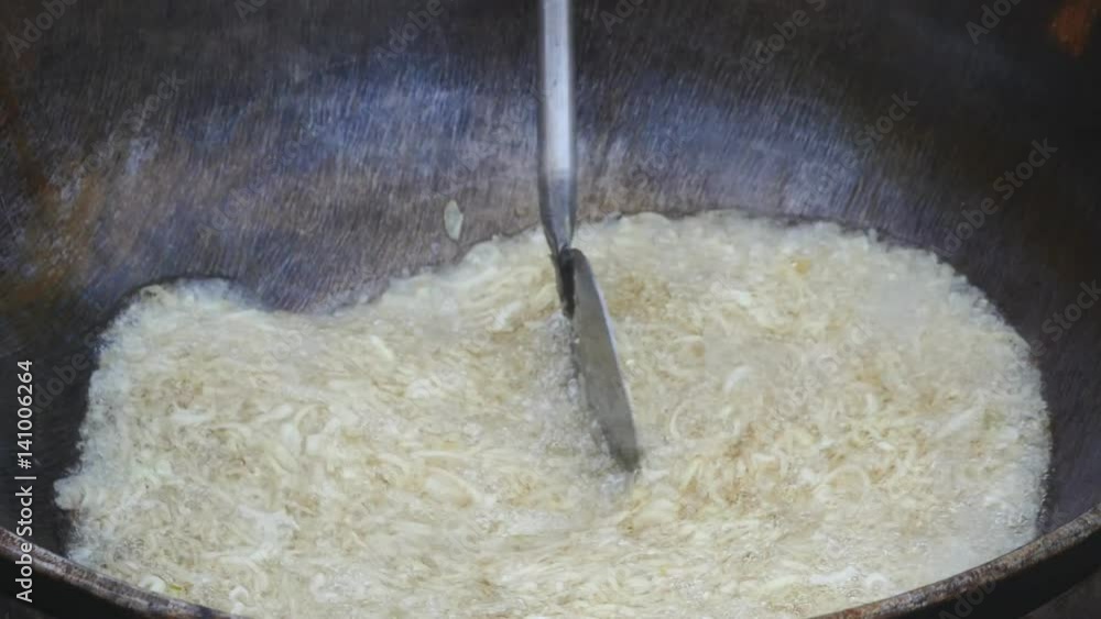 onion rings in yellow oil in fry pan mixed with large spoon onion rings in yellow oil in fry pan mixed with large spoon