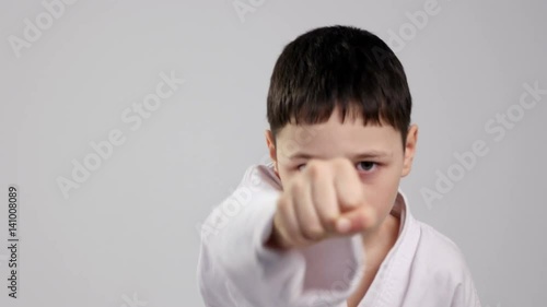 A karateka kid demonstrates two straitforward strikes in studio photo