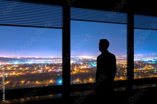 The man stand near the window on the cityscape background