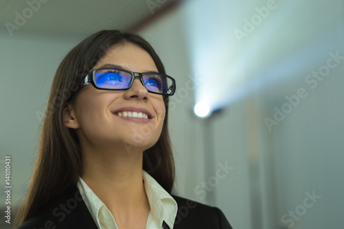 The happy businesswoman with glasses against the background of the projector
