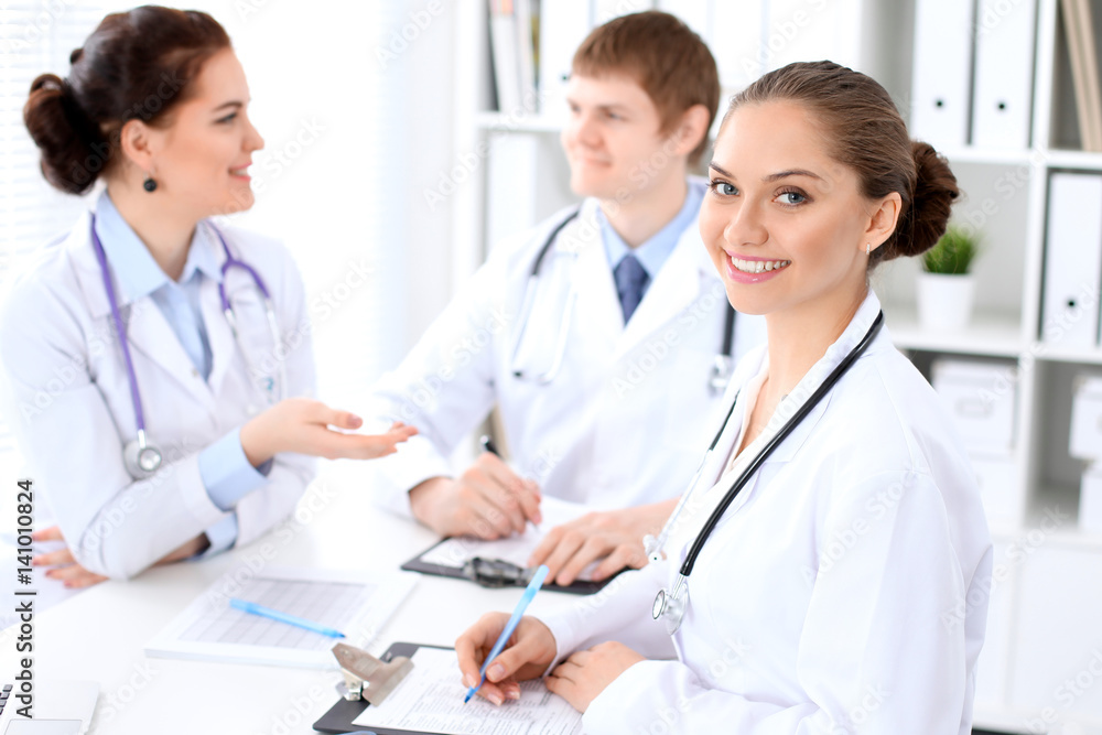 Happy female doctor and medical staff discussing something while sitting at the table. Successful team at health care and medicine concept Happy female doctor and medical staff discussing something while sitting at the table. Successful team at health care and medicine concept