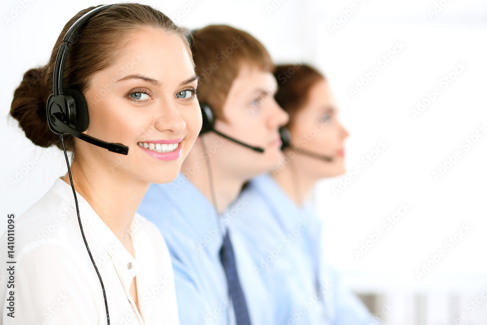 Call center operators. Focus at brunette business woman in headset Call center operators. Focus at brunette business woman in headset