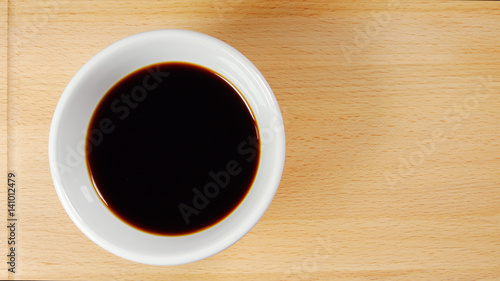 TOP VIEW: Soy sauce cup on a wooden plate