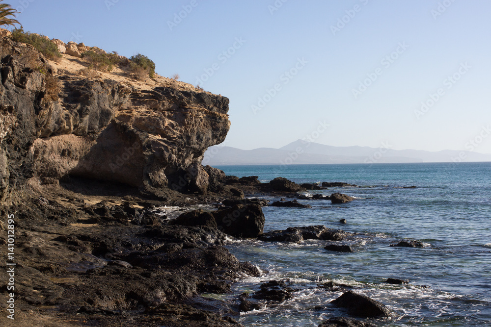 Black rocks of Costa Calma beach. Blue coastline. Playa Barca, Fuerteventura, Canary islands, Spain. Istmo de la pared view