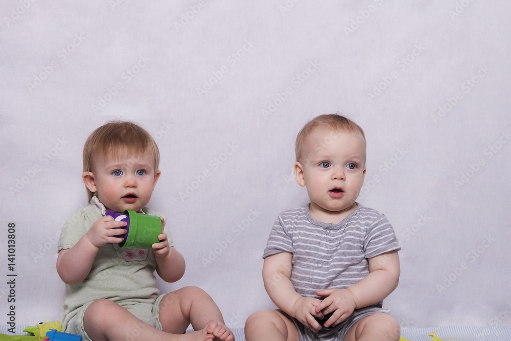 Two pretty little kids sitting with a toys in their hands Two pretty little kids sitting with a toys in their hands